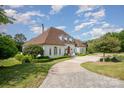 Elegant home featuring a circular driveway, lush landscaping, and architectural charm, surrounded by mature trees at 5400 Challisford Ln, Charlotte, NC 28226