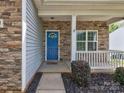 Close-up of the entry showcasing a bright blue door, stone detail, and a small covered porch at 6541 Hasley Woods Dr, Huntersville, NC 28078