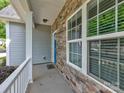 A welcoming front porch featuring stone detailing, white pillars, and an exterior view of the neighborhood at 6541 Hasley Woods Dr, Huntersville, NC 28078