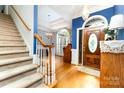 Inviting entryway with hardwood floors, staircase, and decorative floral wallpaper accent wall at 7587 Long Valley Dr, Harrisburg, NC 28075