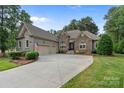 Charming stone and stucco home with a well-manicured lawn and a spacious driveway at 7687 Bermuda Hills Ln, Denver, NC 28037
