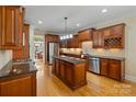 Open kitchen with island, stainless appliances, wooden cabinets and eat-in dining nook at 7687 Bermuda Hills Ln, Denver, NC 28037