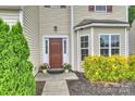 Inviting front entrance with a dark brown door, manicured landscaping, and ample natural light at 9321 Bradstreet Commons Way, Charlotte, NC 28215