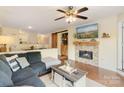 Cozy living room featuring a stone fireplace, ceiling fan, and access to the kitchen at 108 Pier 33 Dr # 414, Mooresville, NC 28117