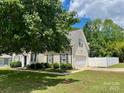 View of charming white home with black shutters, fenced yard and two-car garage at 13241 Woodland Farm Dr, Charlotte, NC 28215