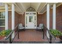 Inviting front porch featuring tile flooring, comfortable seating, and a brick surround at 14340 Kendalton Meadow Dr, Mint Hill, NC 28227