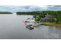 Waterfront home and dock with multiple boat slips on a serene lake surrounded by lush greenery at 19523 Sunnypoint Ct, Cornelius, NC 28031