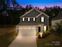Two-story home featuring a two-car garage, landscaped yard, and classic architectural details at dusk at 2012 Slippery Rock Ln, Monroe, NC 28112