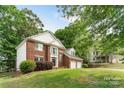 Charming two-story brick home with a well manicured lawn, mature trees, and a two-car garage, creating a welcoming curb appeal at 2608 Yarrow Rd, Charlotte, NC 28213