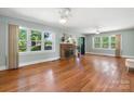 Inviting living room featuring hardwood floors, a cozy stone fireplace, and multiple windows offering natural light at 3418 Sulphur Springs Ne Rd, Hickory, NC 28601