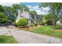 View of a two-story house with a brick chimney, gray siding, and a long driveway leading to the property at 3918 Rea Rd, Charlotte, NC 28226