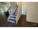 Interior view of the entryway featuring dark wood flooring, a staircase, and a glimpse into the adjacent rooms at 4025 Grommet Ct, Matthews, NC 28105