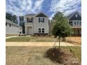 Two-story home featuring stone accents, gray siding, black shutters, and a small front yard tree at 4025 Grommet Ct, Matthews, NC 28105