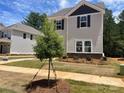 Two-story home featuring stone accents, gray siding, black shutters, and a small front yard tree at 4025 Grommet Ct, Matthews, NC 28105