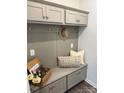 A mudroom area with cabinets, bench, storage, hooks, pillows, basket, and a neutral color scheme at 5817 Tuckaseegee Rd, Charlotte, NC 28208