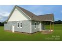 View of the back exterior with covered porch, brick foundation and rear entrance at 6203 Flay Rd, Cherryville, NC 28021