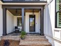 Inviting covered front porch with stylish black accents, brick flooring, outdoor seating, and decorative flower pot at 8108 Farm Crossing Ln # 26, Huntersville, NC 28078