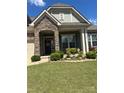 Close up of a home featuring a stone archway entry and a well-maintained lawn with colorful landscaping at 10039 St Kitts Landing Ln, Charlotte, NC 28278
