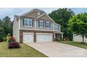 Charming two-story home with a manicured lawn, featuring a two-car garage and stone accents at 109 Meadow Stream Dr, Mount Holly, NC 28120