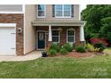Inviting front porch with stone accents and a beautifully landscaped front yard with colorful roses at 109 Meadow Stream Dr, Mount Holly, NC 28120