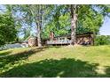 View of the back of the brick home, with a wooden deck, and a large grassy yard at 1211 Starlight Dr, Shelby, NC 28152