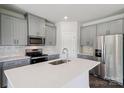 Bright kitchen featuring gray cabinets, stainless steel appliances, white backsplash, and a large island with a sink at 1712 Braemar Village Dr, Monroe, NC 28110