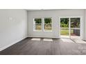 Living room with dark wood floors, natural light from the windows and glass door with a view of the backyard at 1712 Braemar Village Dr, Monroe, NC 28110