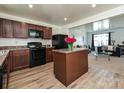 Well-lit kitchen with dark cabinets, black appliances, an island, and an open view to the living room at 2715 Sydney Overlook Ln, Charlotte, NC 28269