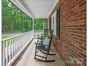 Quaint front porch featuring rocking chairs, complemented by a charming brick facade and a peaceful outdoor setting at 300 Hugh Crocker Rd, Matthews, NC 28104