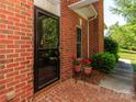 Close-up of brick entrance featuring potted plants, glass storm door, and well-maintained exterior at 532 Wilmslow Rd, Rock Hill, SC 29730