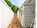 A narrow side yard with a gravel path and a white privacy fence at 7129 Stonington Ln, Charlotte, NC 28227