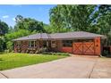 Charming brick ranch home with decorative shutters, mature trees and a striking wooden crossbuck garage door at 851 Gist Rd, Rock Hill, SC 29732