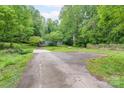 A long driveway leading to a house with ample parking, a shed, an American flag, and trees around it at 857 Hills Rd, Belmont, NC 28012