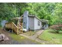 Side view of a cozy home featuring a chimney, wooden stairs, mature trees and vibrant landscaping at 857 Hills Rd, Belmont, NC 28012