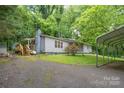 Cozy home with driveway, featuring a covered parking area and surrounded by vibrant landscaping and mature trees at 857 Hills Rd, Belmont, NC 28012