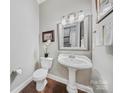 Stylish half bathroom with pedestal sink, decorative mirror, and wood flooring at 9075 Blue Ridge Dr, Indian Land, SC 29707