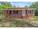 Classic brick home with black shutters, covered porch, and manicured landscaping at 1154 Stringfellow Rd, Chester, SC 29706
