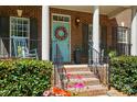 Inviting front porch with a decorative wreath, seasonal flowers, and a rocking chair at 129 Willow Tree Ln, Mount Holly, NC 28120
