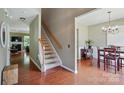 Inviting entryway featuring hardwood floors, staircase, and open view into the dining area with elegant chandelier at 14402 Asheton Creek Dr, Charlotte, NC 28273