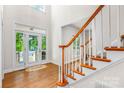 Bright foyer featuring wood floors, staircase with wood railing, and a front door with glass panels at 14426 Harvington Dr, Huntersville, NC 28078