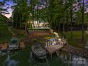 Scenic aerial view of a lakefront property featuring a private dock, boat, pool, and elegant home nestled in lush greenery at 19614 Meta Rd, Cornelius, NC 28031