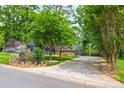 Scenic driveway leading to a charming home surrounded by mature trees and lush landscaping at 4609 Rounding Run Rd, Charlotte, NC 28277