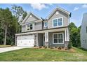 Two-story home featuring gray siding, a two-car garage, and a well-manicured lawn at 5103 Heathland Dr # 50, Charlotte, NC 28215