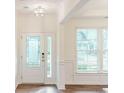 Bright foyer with wainscoting, light hardwood floors, transom window and decorative glass front door at 8286 Ashvale Nw St, Concord, NC 28027