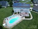 Aerial view of a home with a solar roof, large deck, and an inviting kidney-shaped pool at 100 Oakwood Meadow Dr, Mooresville, NC 28115