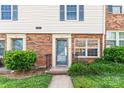 Close-up of a well-kept townhouse entrance with brick facade, garden and manicured lawn at 1228 Archdale Dr # H, Charlotte, NC 28217