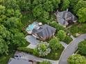 Aerial view of a home surrounded by mature trees, pool, patio, and well maintained yard at 13029 Whisper Creek Dr, Charlotte, NC 28277