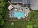 Aerial view of a backyard pool with hot tub, lounge chairs, flowers, and an umbrella with patio at 13029 Whisper Creek Dr, Charlotte, NC 28277