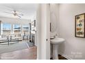 Cozy powder room showcasing pedestal sink with decorative mirror and an adjacent living room with fireplace and abundant natural light at 14015 Wilson Mac Ln, Charlotte, NC 28278
