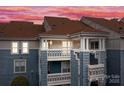 A beautiful exterior showcasing a multi-story condo building with charming balconies under a pink and purple sky at 18669 Vineyard Point Ln, Cornelius, NC 28031